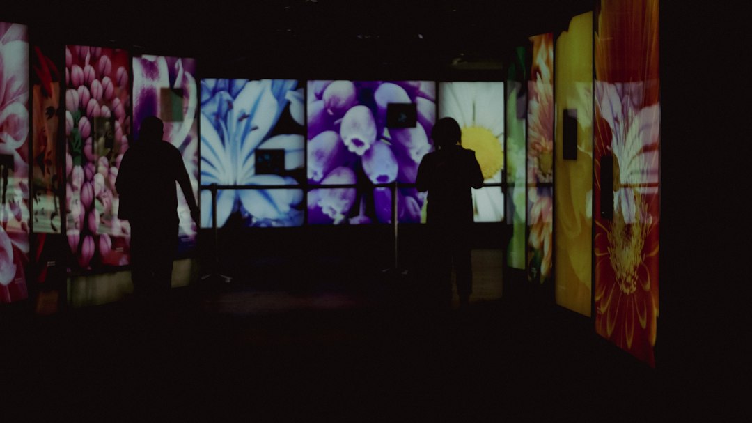 Visitors viewing colorful digital artwork on large gallery screens