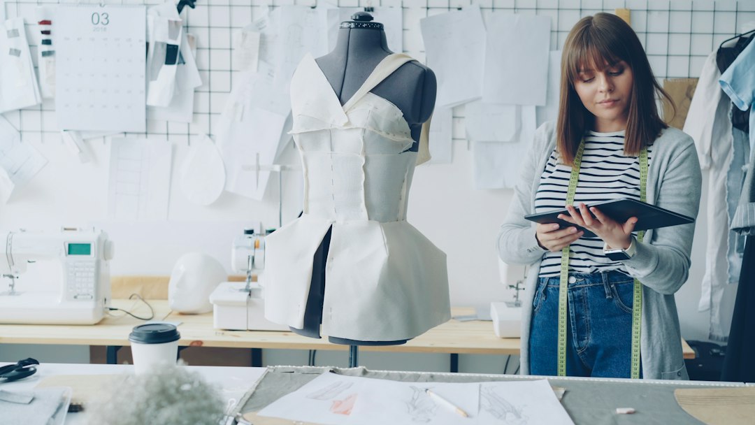 Fashion designer using a tablet beside garments in a studio